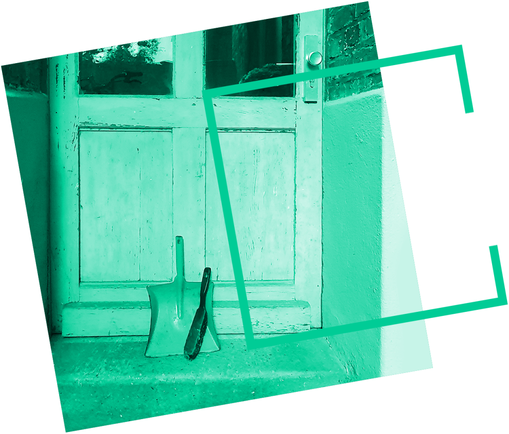 Kehrblech und Besen sind an eine Tür gelehnt. Sie symbolisieren ein verlassenes Haus, das dem Braunkohlebagger weichen muss.